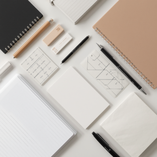 Conjunto de material de papelaria corporativa, destacando resmas de papel A4, blocos de notas, pastas de arquivo e instrumentos de escrita profissionais.